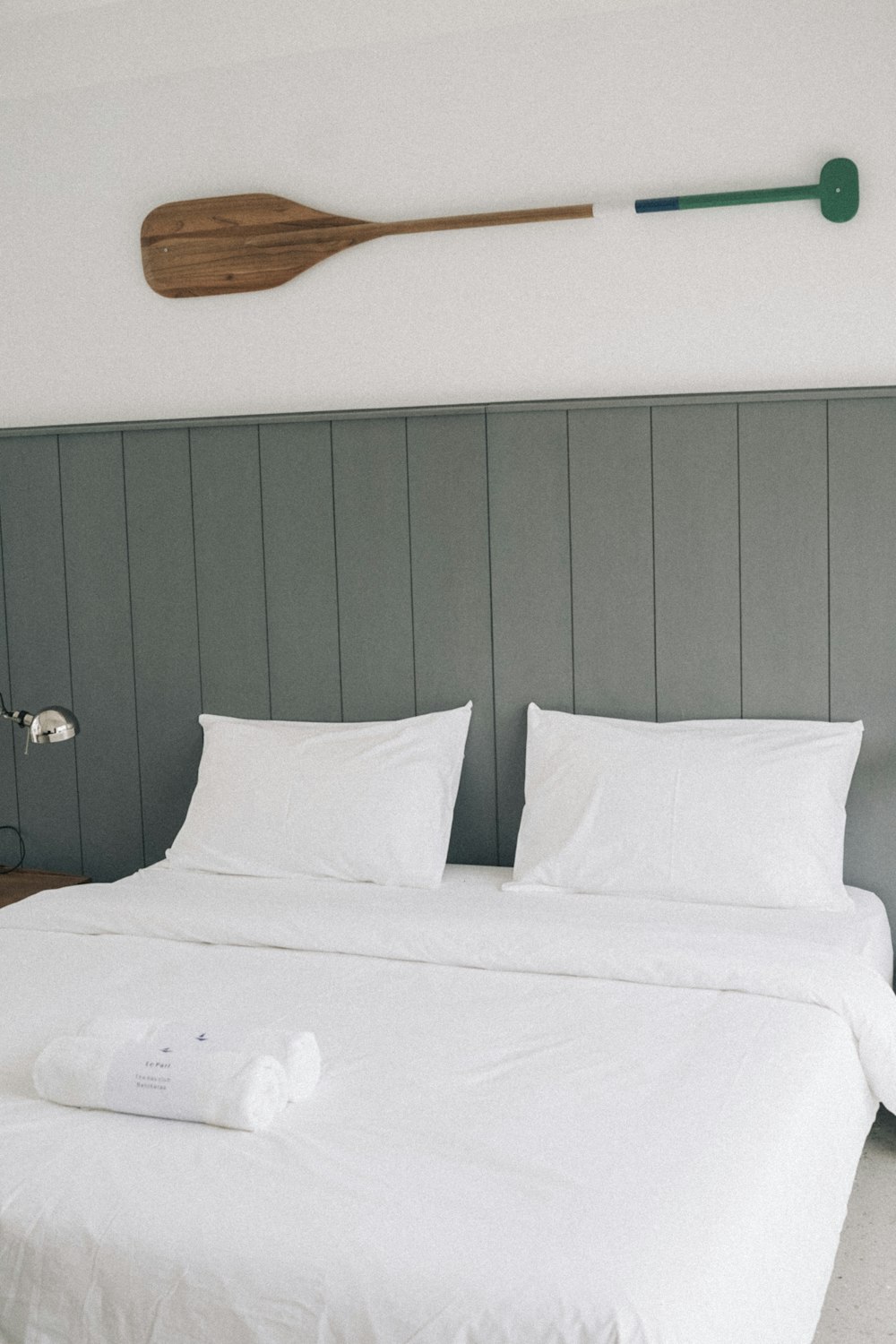 a bed with white sheets and a wooden paddle on the wall