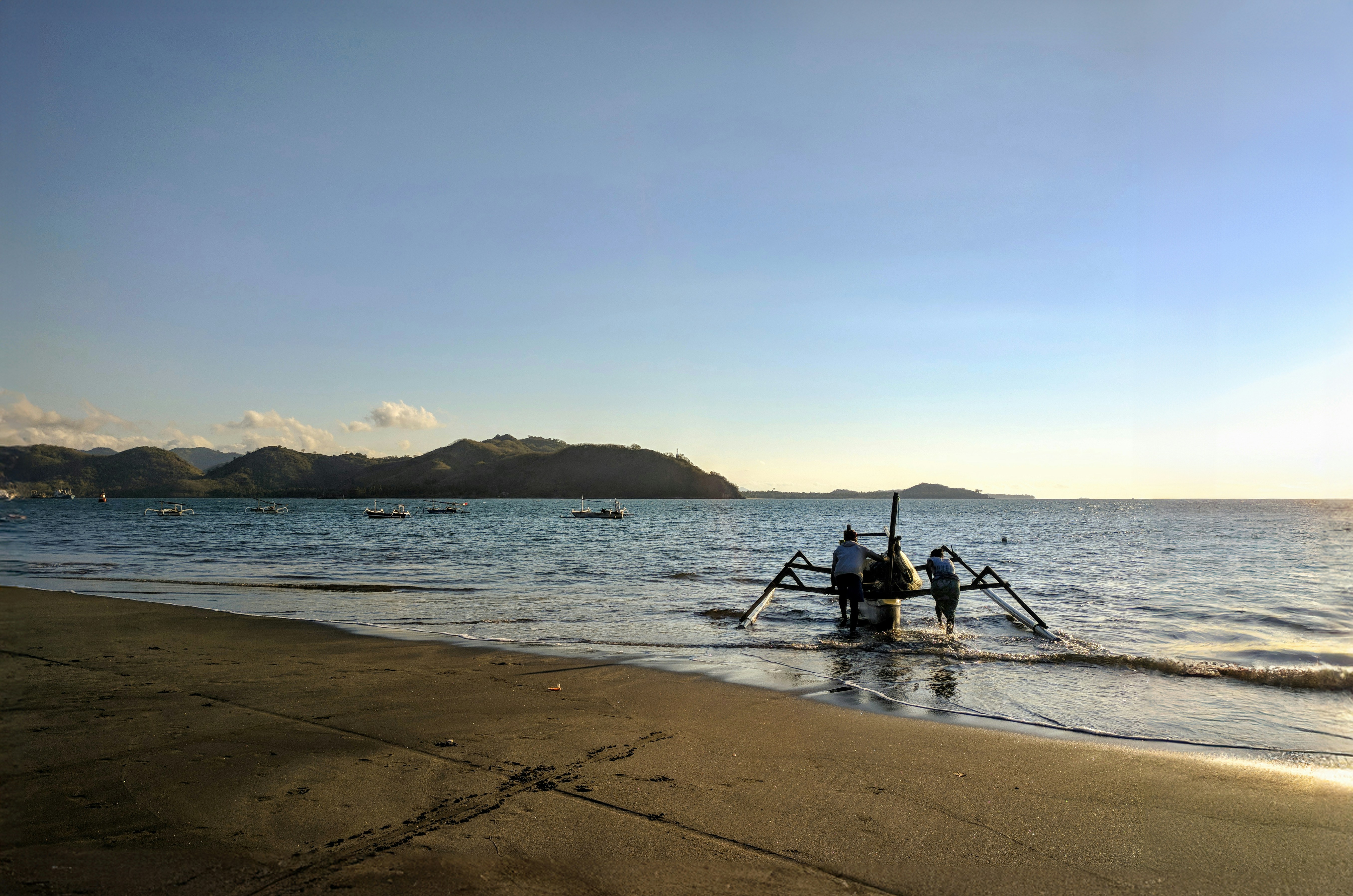 a boat sitting on top of a beach next to the ocean