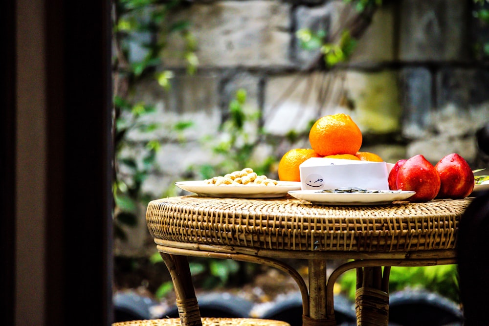 a wicker table with a bowl of fruit on it