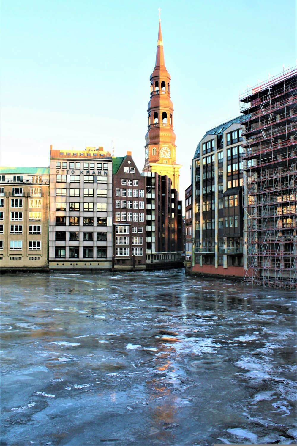 a clock tower towering over a city with ice on the water