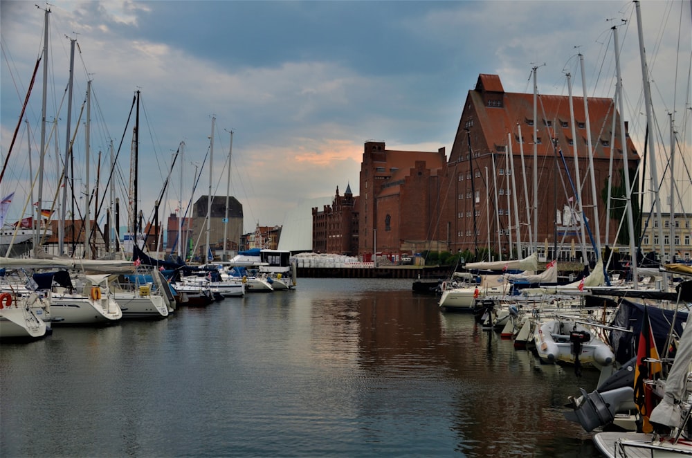 a harbor filled with lots of sailboats under a cloudy sky