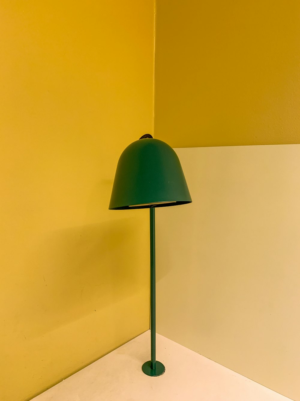 a green lamp sitting next to a yellow wall