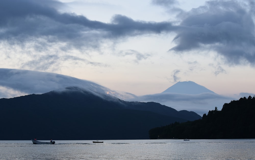 a boat floating on top of a lake under a cloudy sky