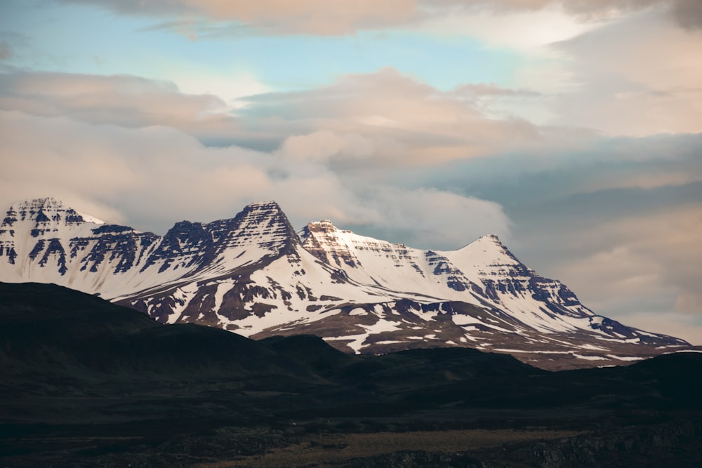 a snow covered mountain with clouds in the background