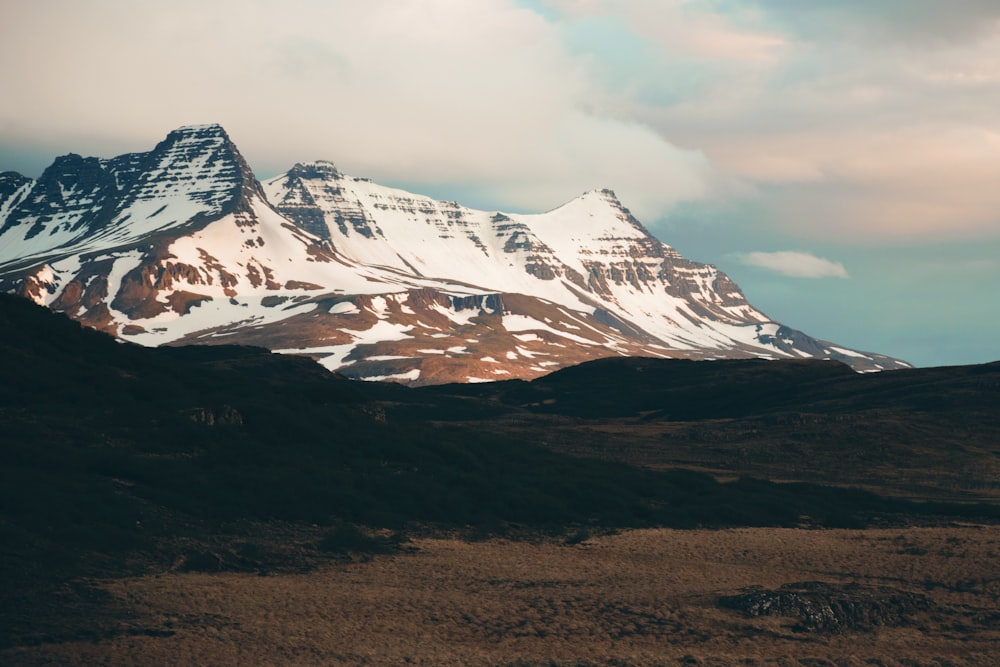 a snow covered mountain with a few clouds in the sky