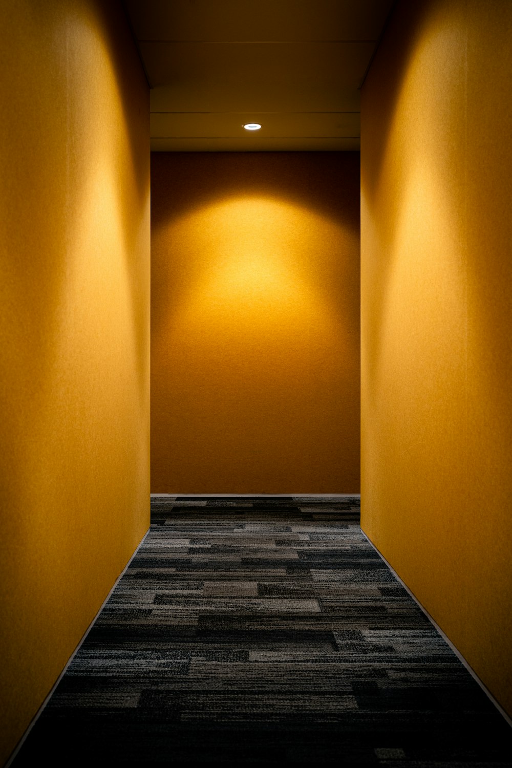 an empty hallway with yellow walls and a black carpet
