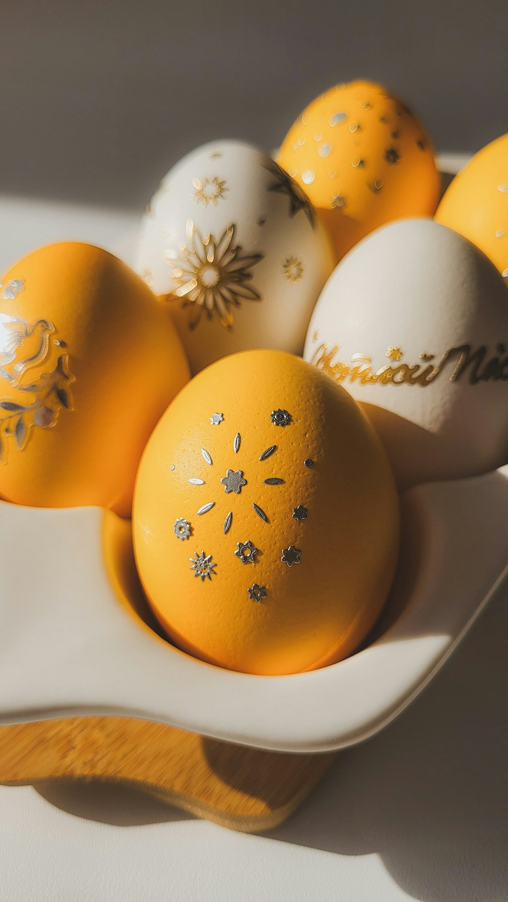 a white bowl filled with yellow and white decorated eggs