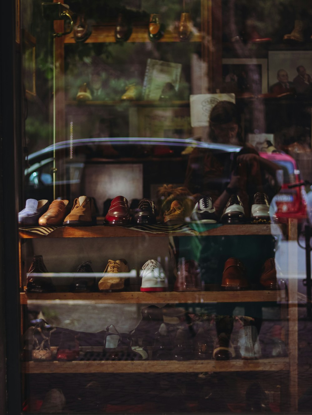 a store window with shoes and a car in the reflection