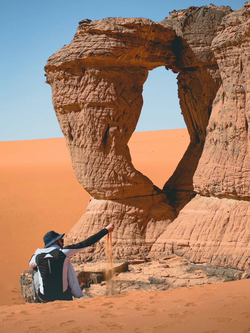 a person sitting on a rock formation in the desert