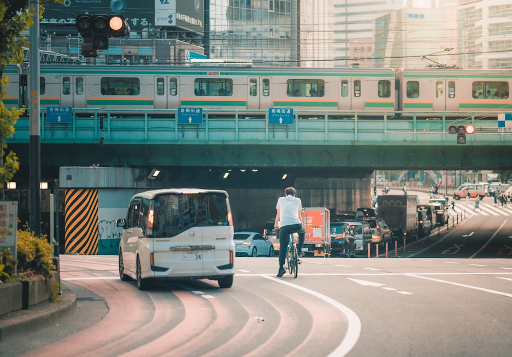 a man riding a bike down a street next to a train