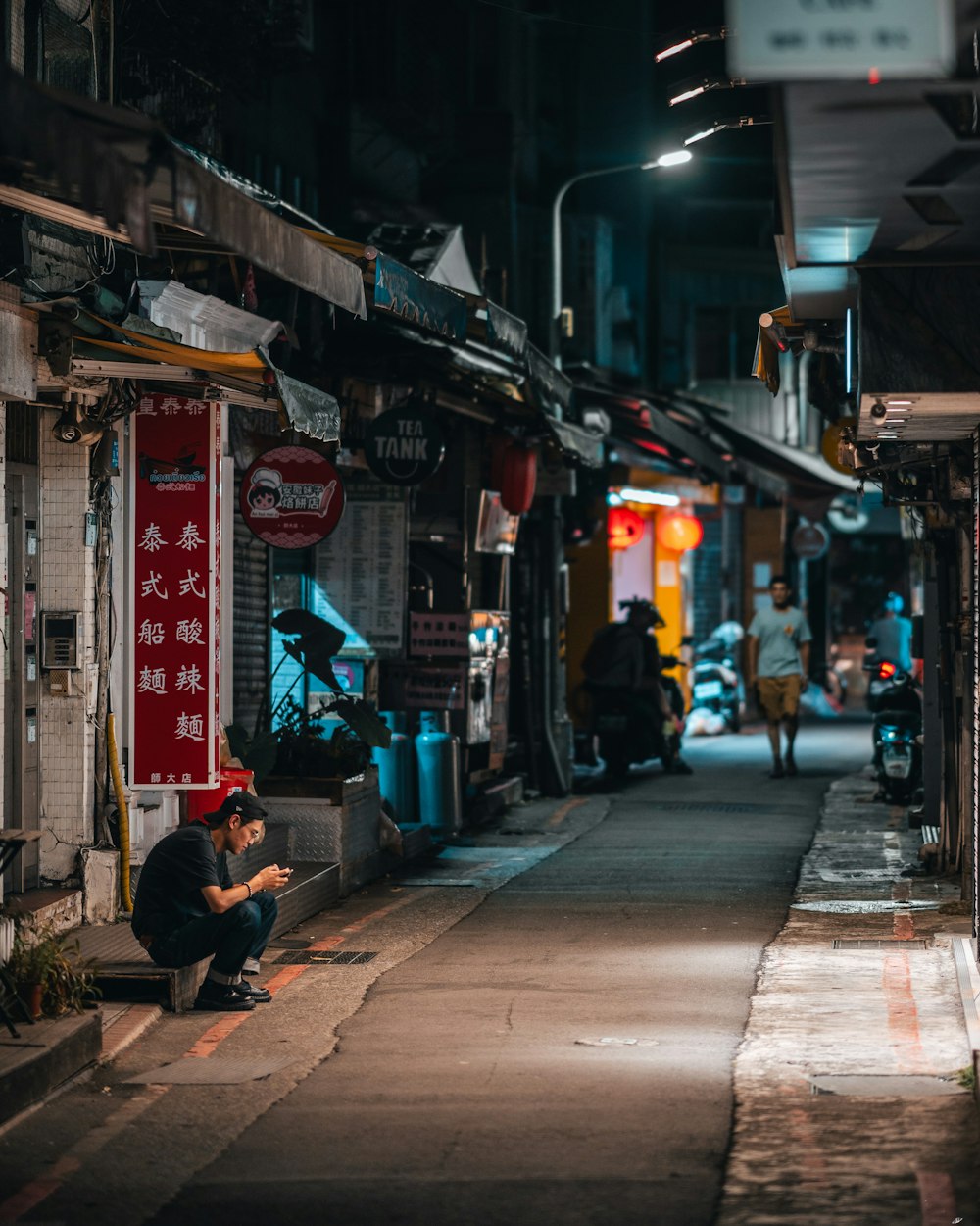 a man sitting on a bench in an alley