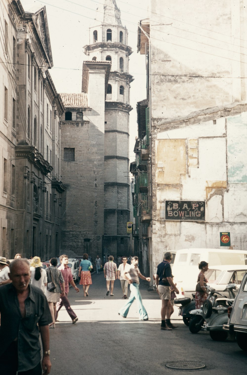 a group of people walking down a street next to tall buildings