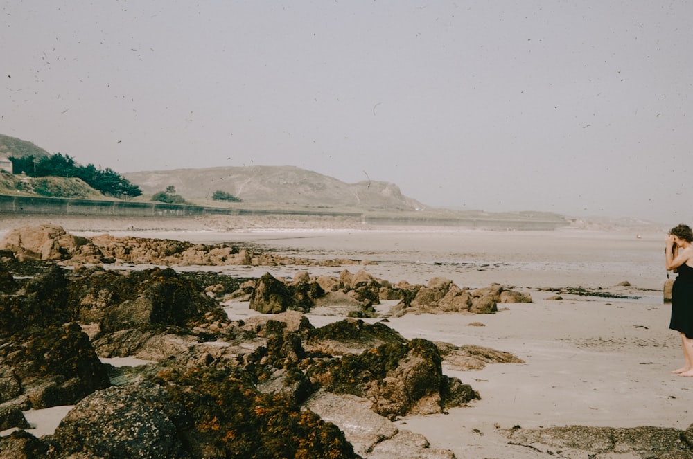 a woman standing on top of a sandy beach