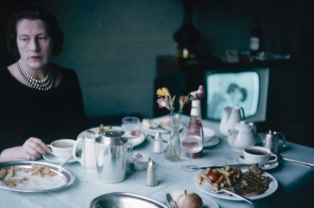 a woman sitting at a table with plates of food