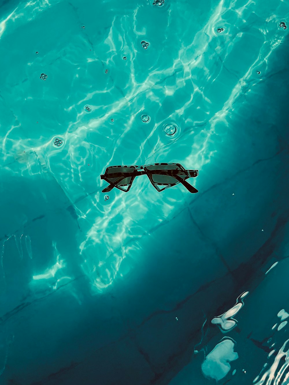 a pair of sunglasses floating in a pool of water