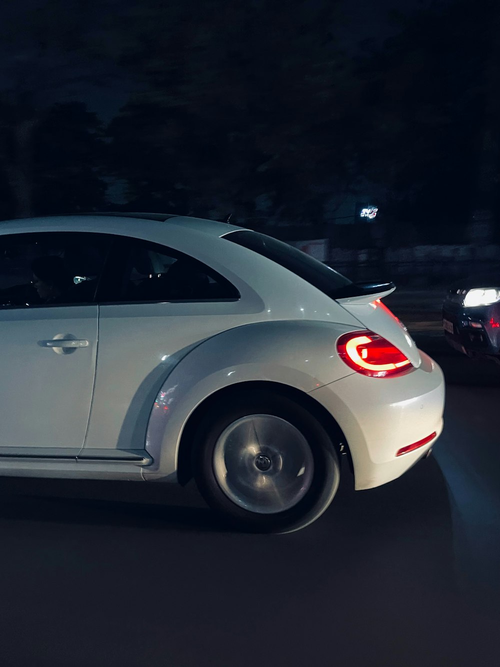 a white car driving down a street at night