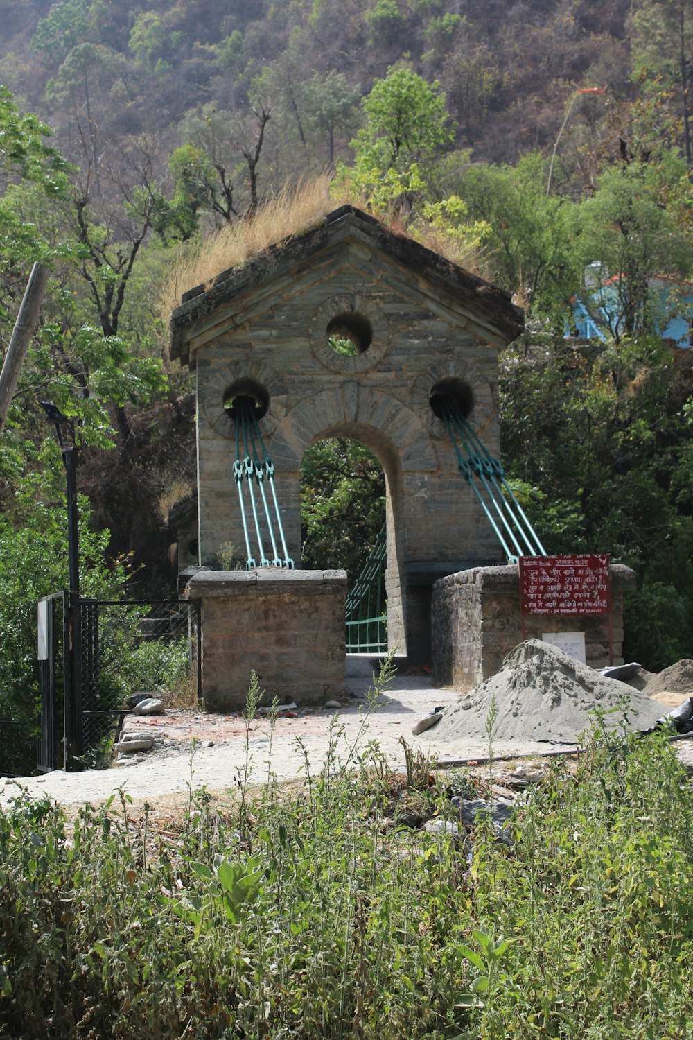 a stone building with a grass roof and a gate