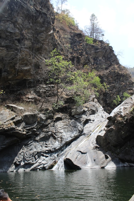 a man sitting on a rock next to a body of water