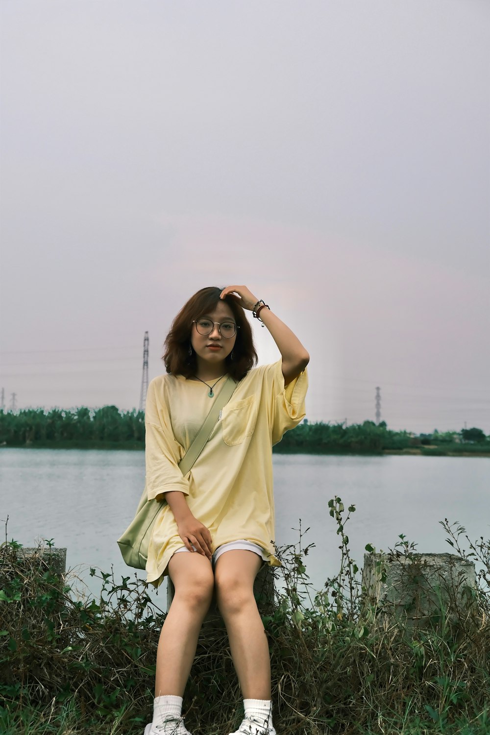 a woman sitting on a rock next to a body of water