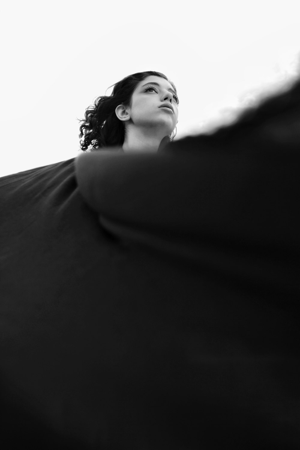 a black and white photo of a woman looking up