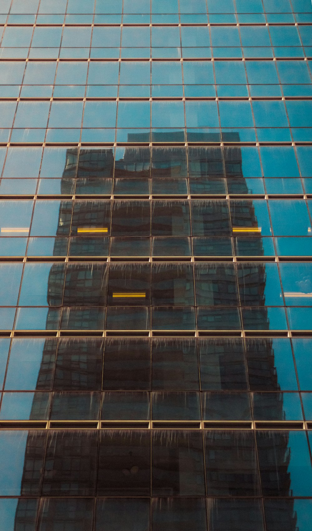a very tall building reflected in the windows of another building