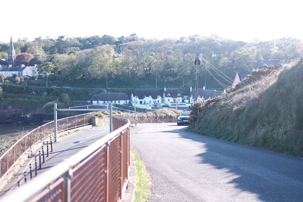 a car driving down a road next to a lush green hillside