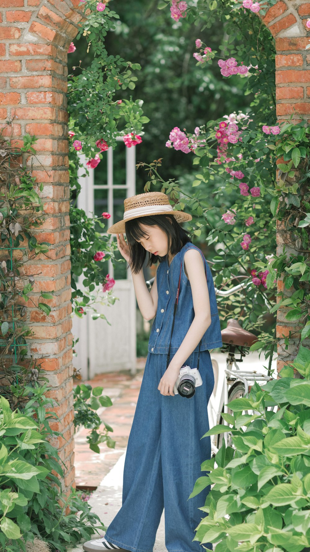 a woman in a blue jumpsuit and a straw hat
