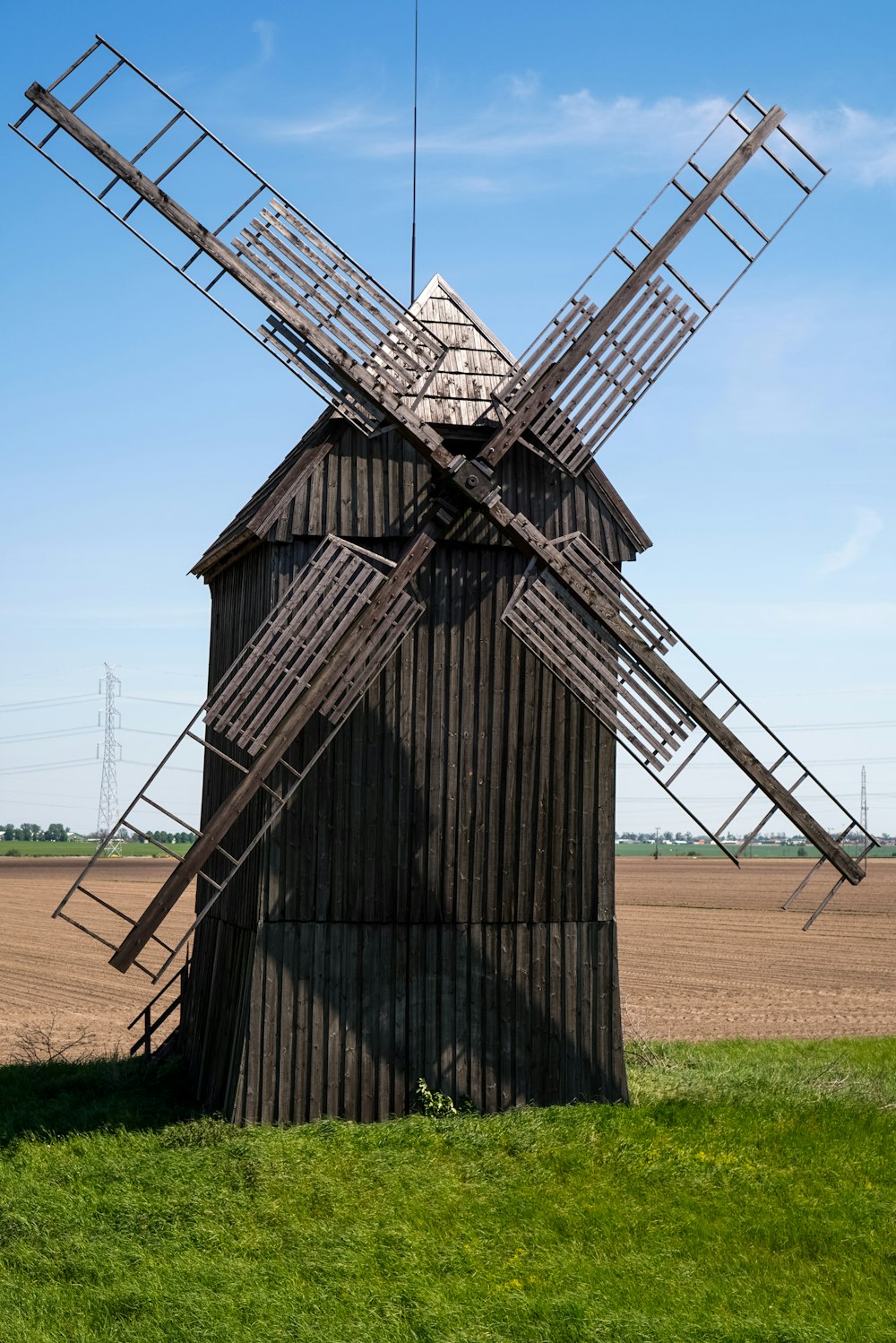 a wooden windmill sitting on top of a lush green field