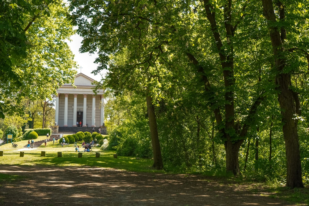 a small white building surrounded by trees in a park