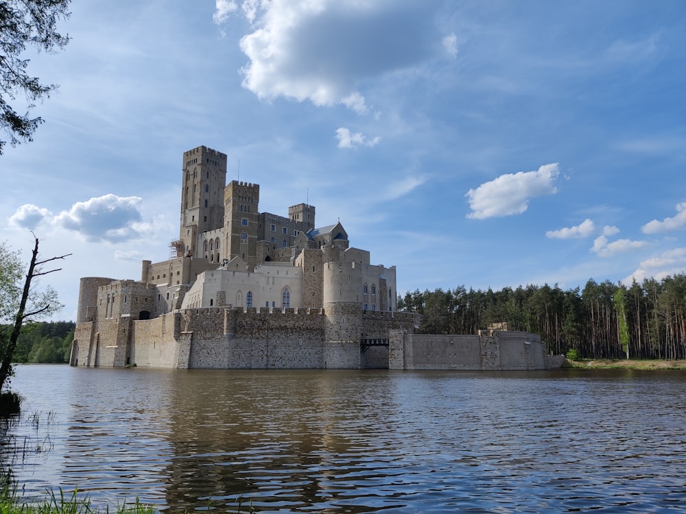 a castle sitting on top of a lake next to a forest