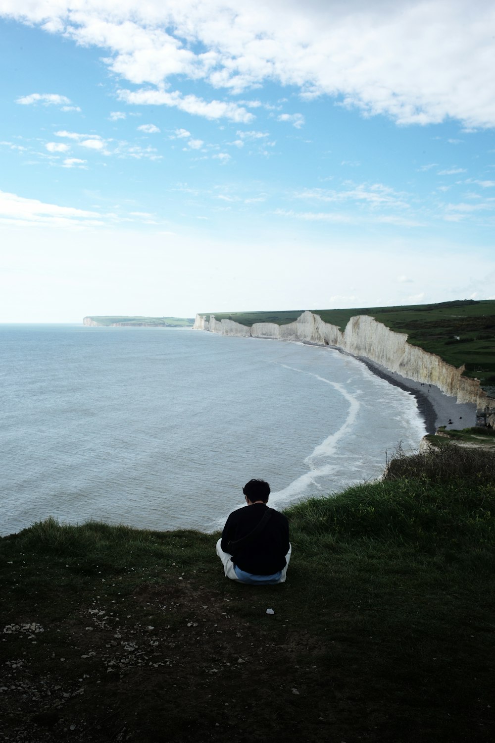 a man sitting on a cliff overlooking the ocean