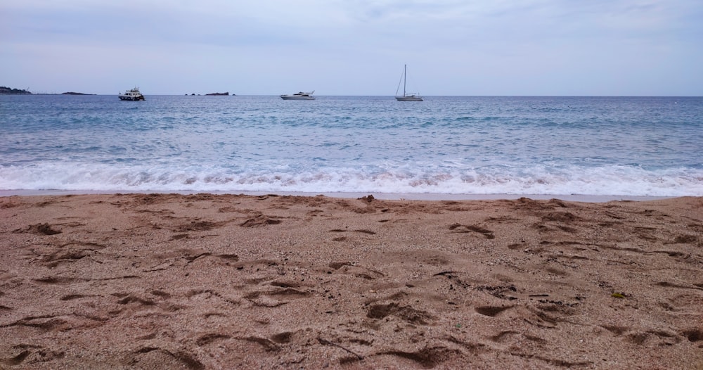 a sandy beach with boats in the distance
