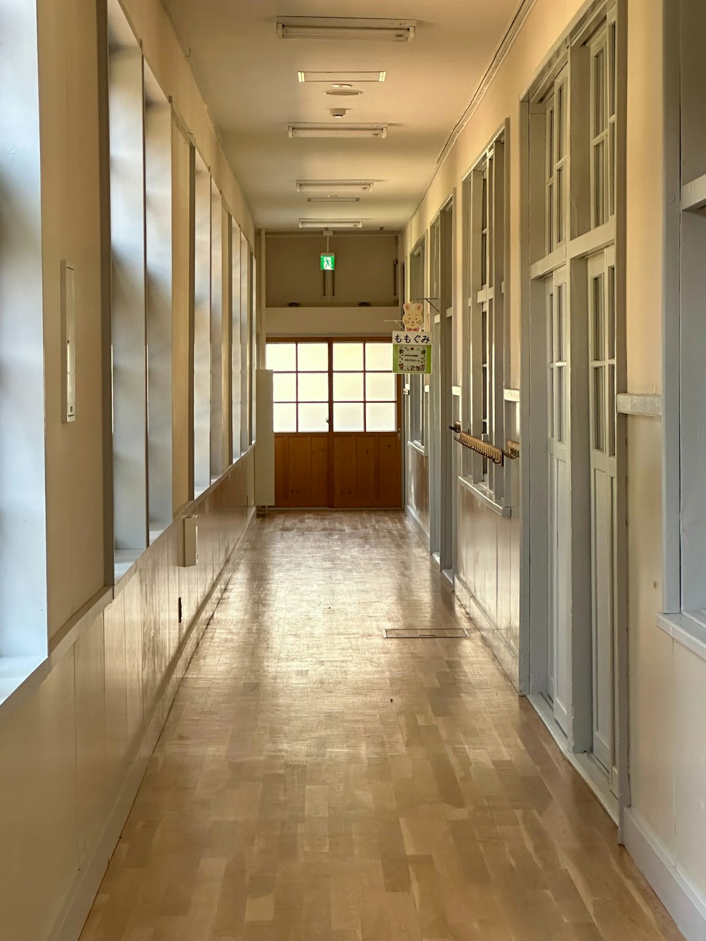 Un largo pasillo con suelos y ventanas de madera