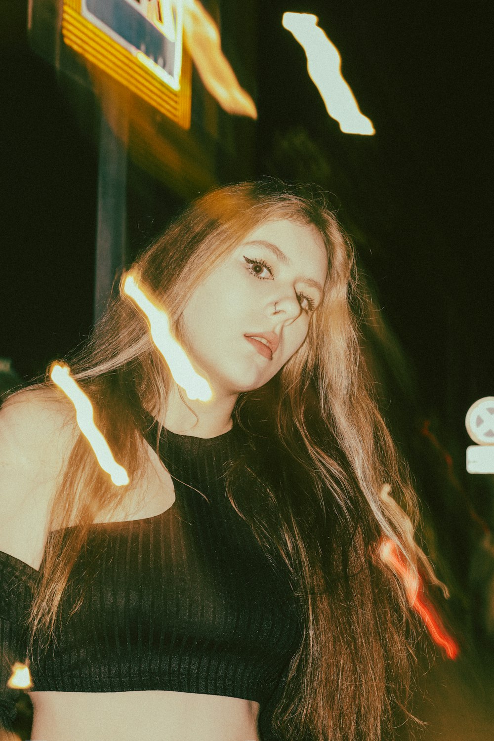 a woman with long hair standing in front of a neon sign