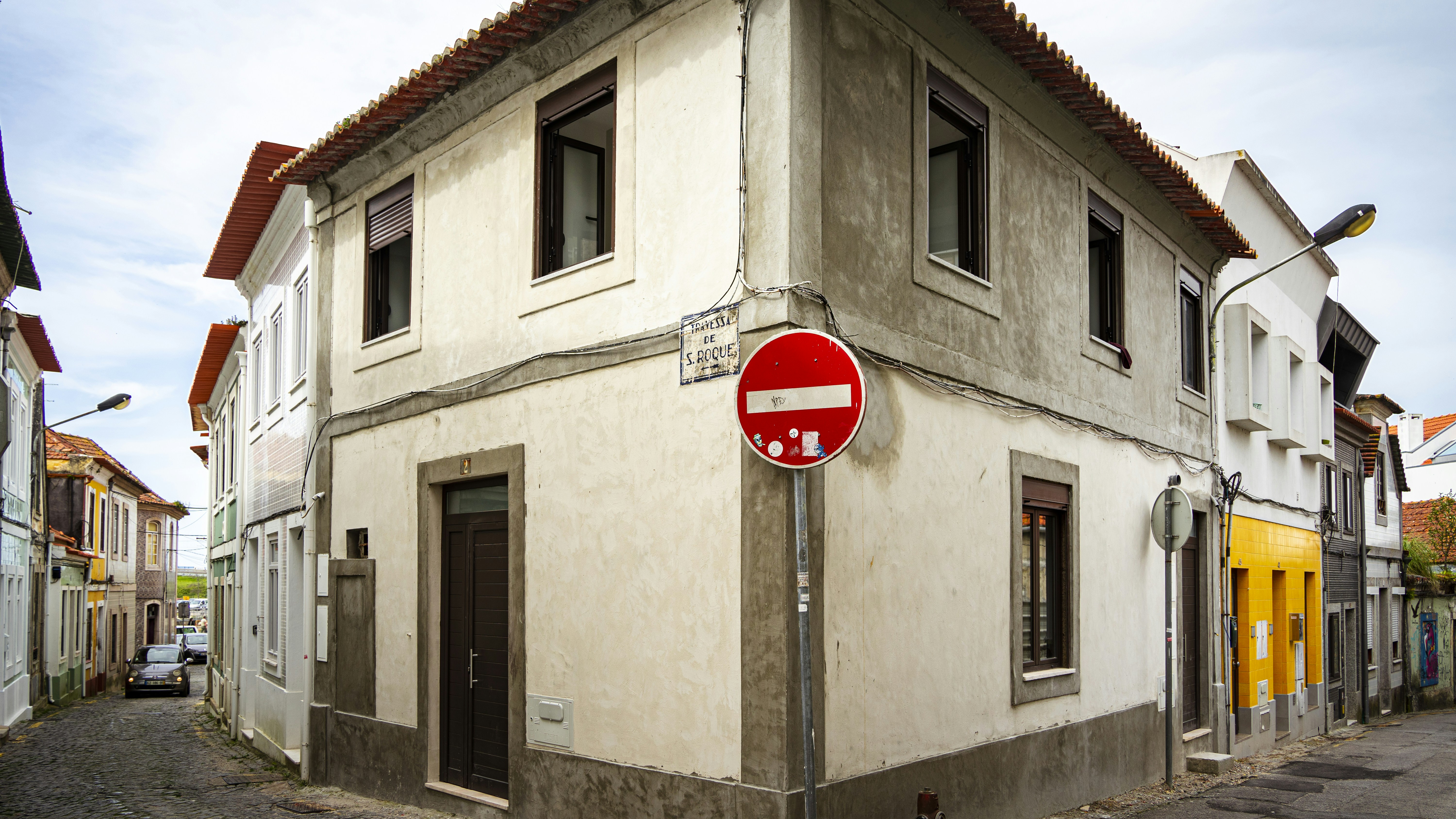 A modern 'For Sale' sign standing in the manicured front lawn of a beautiful suburban home on a bright, sunny day.
