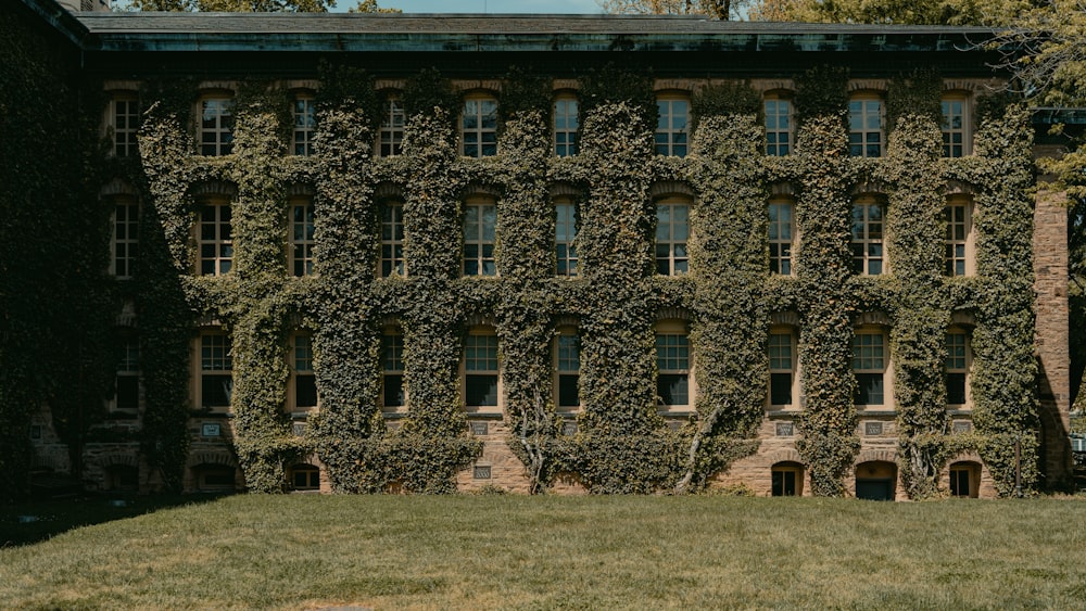a large building covered in vines next to a lush green field