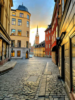 a cobblestone street with a church steeple in the background