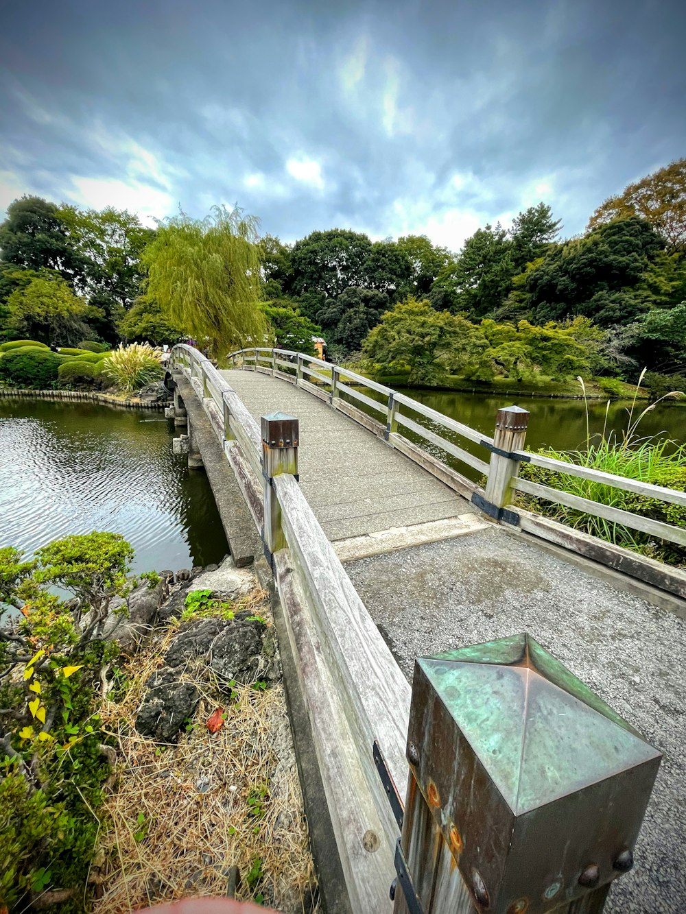 a wooden bridge over a small pond in a park