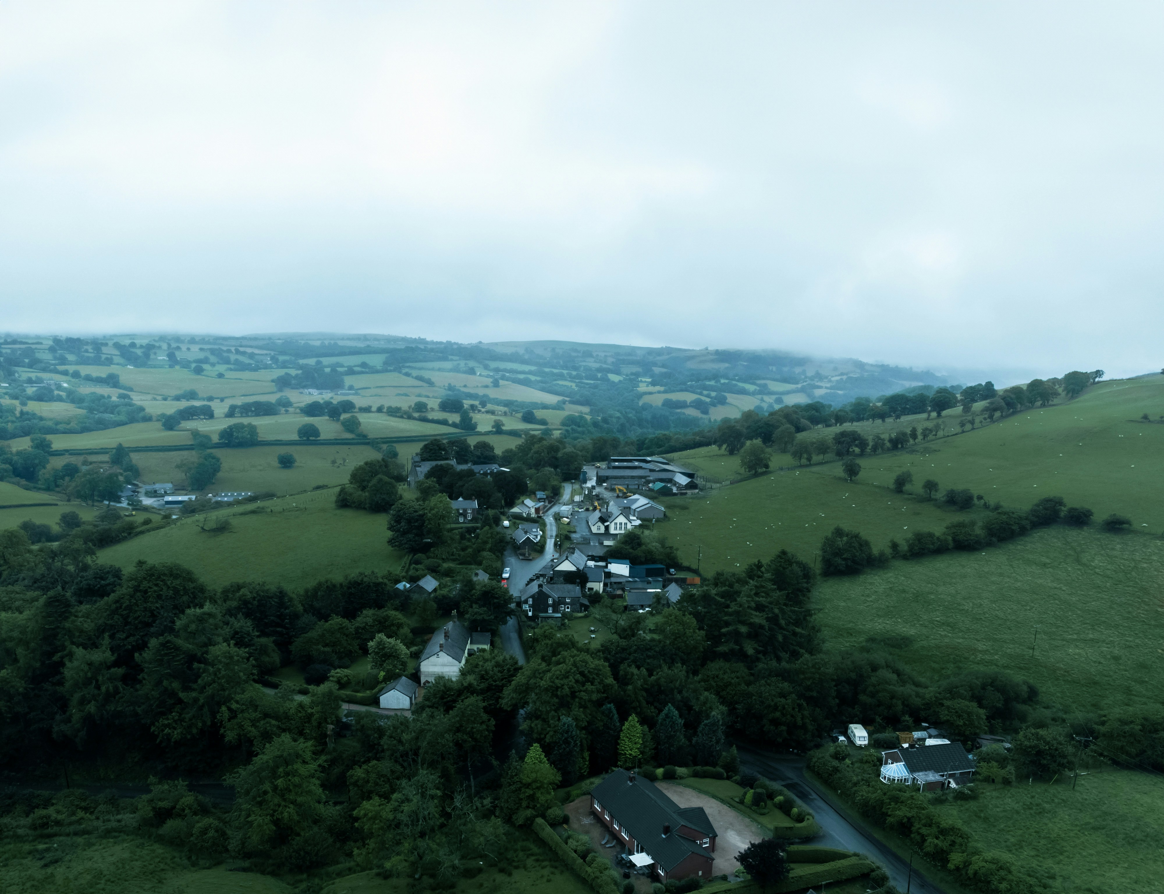 an aerial view of a small town surrounded by trees, Country side in Wales