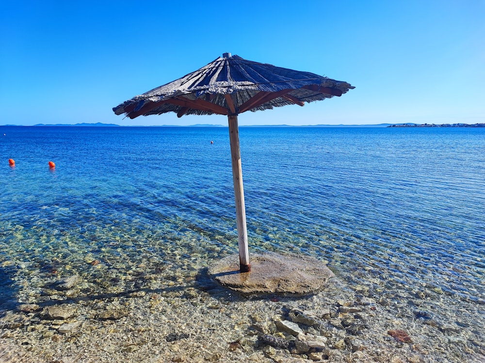 a beach umbrella sitting on top of a rock near the ocean