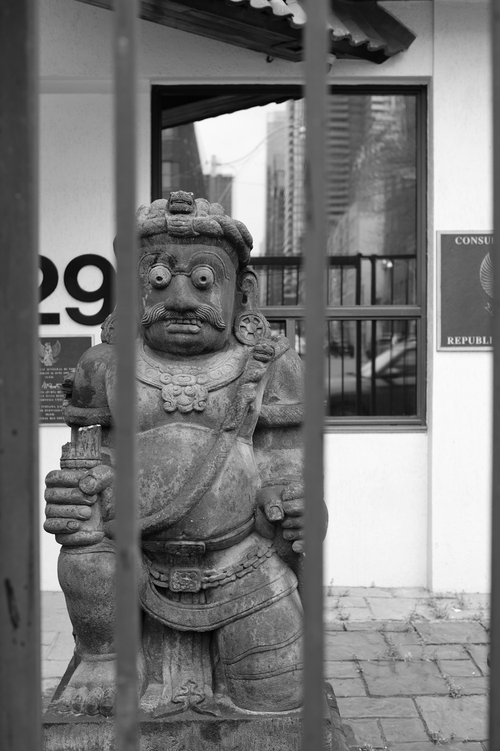 a statue in front of a building behind a fence