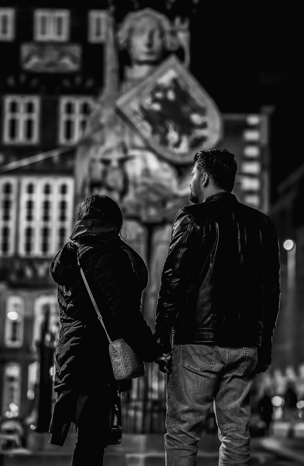 a man and a woman holding hands on a city street