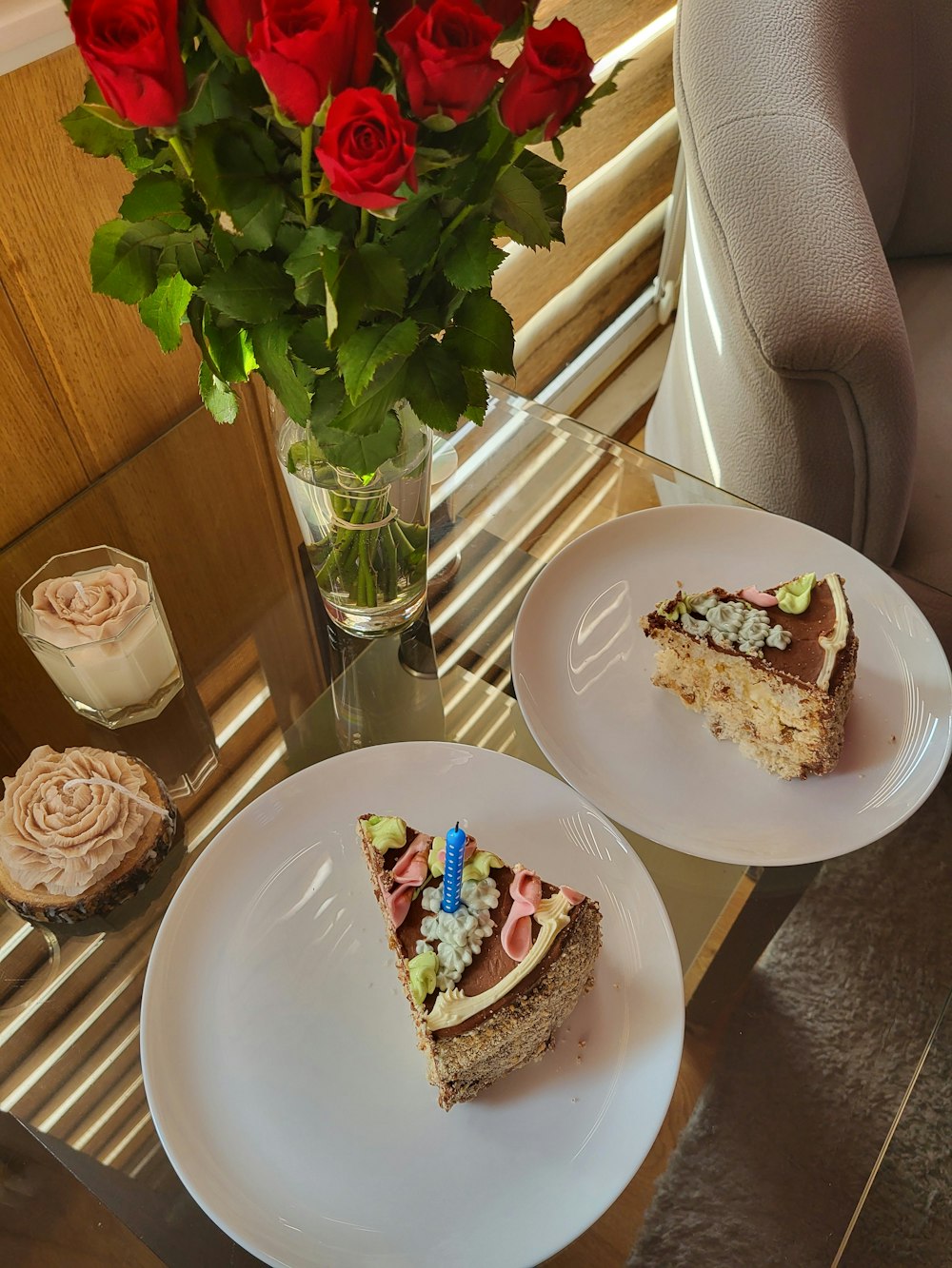 two plates with slices of cake and a vase of roses