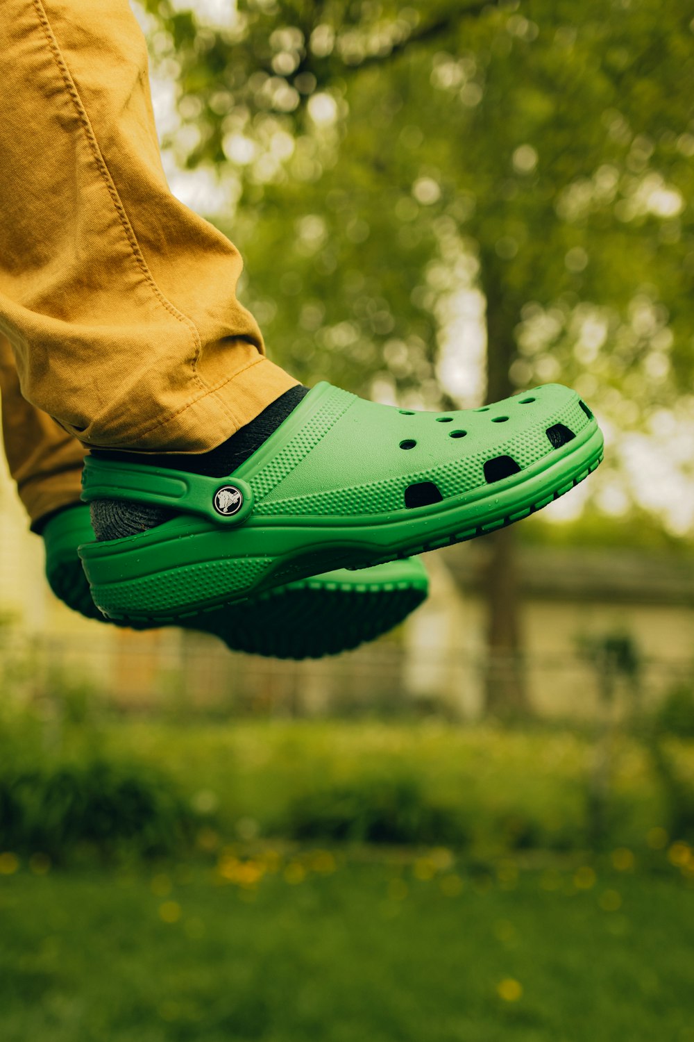 a person wearing a green clogger shoe in a park