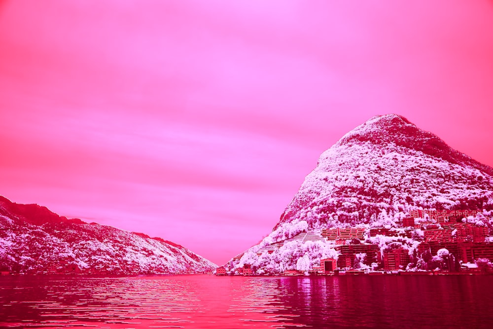 a pink sky over a mountain and a body of water