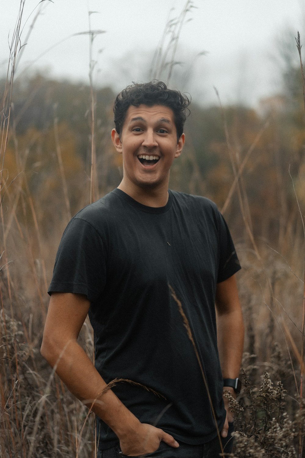 a young man standing in a field of tall grass