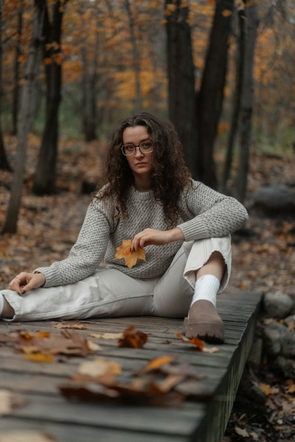 a woman sitting on a wooden platform in the woods