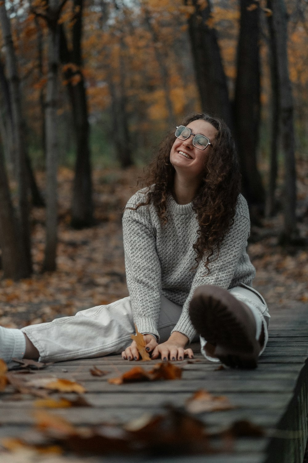 a woman sitting on a wooden bench in the woods