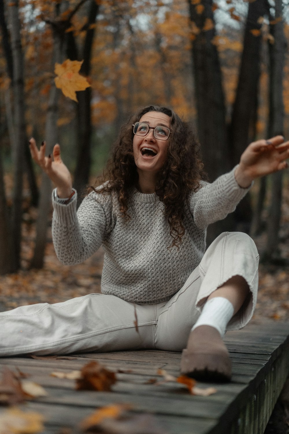 a woman sitting on a wooden platform in the woods