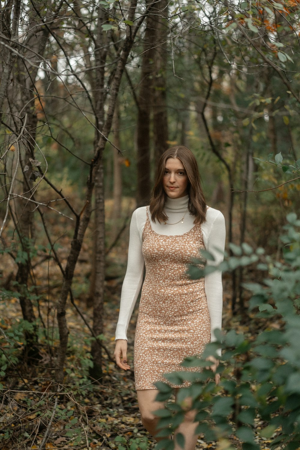 a woman in a dress is walking through the woods